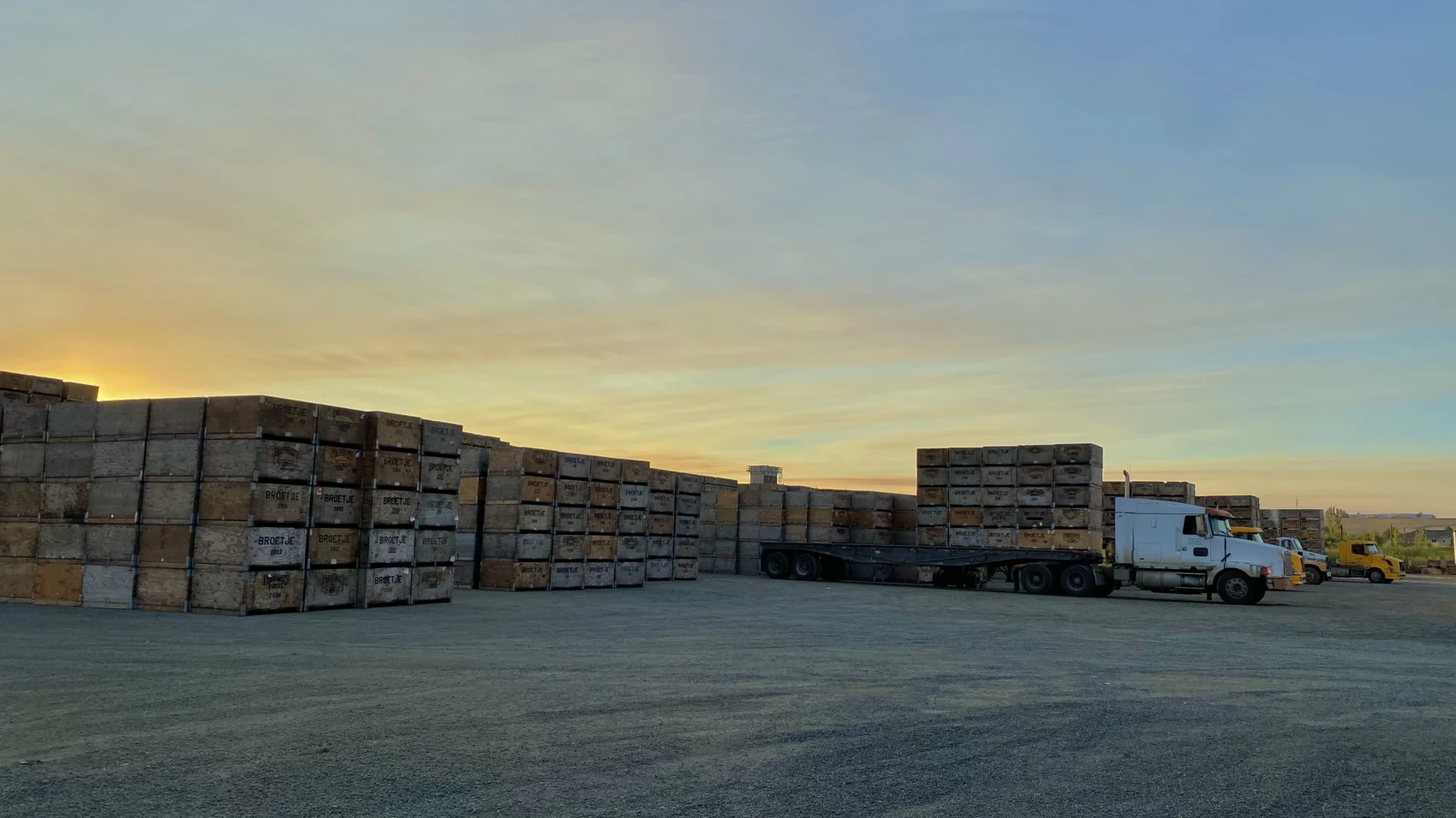 Apple bins stacked and a truck at dusk.